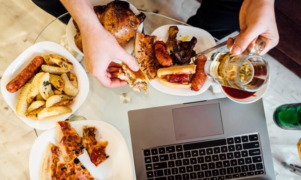 Top view of a man's hands holding a lot of food, symbolizing unhealthy eating habits associated with binge eating disorder.