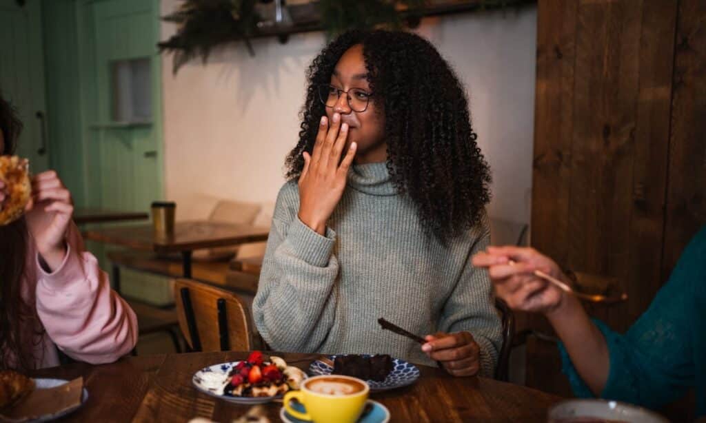 Smiling woman enjoying a meal, representing a positive relationship with eating.